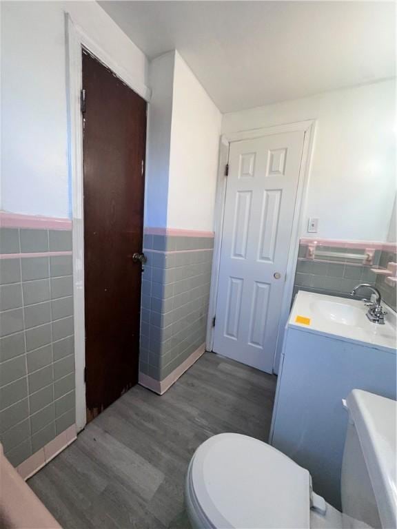 bathroom featuring hardwood / wood-style floors, vanity, toilet, and tile walls