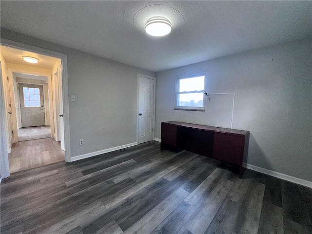 unfurnished bedroom with multiple windows and dark wood-type flooring