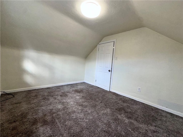 bonus room with a textured ceiling, dark carpet, and lofted ceiling