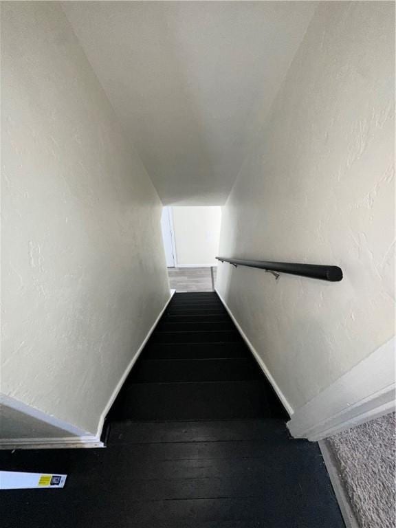 stairway featuring wood-type flooring and vaulted ceiling