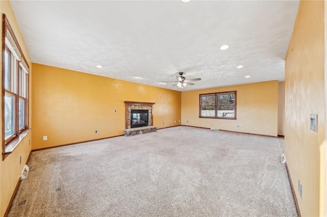 unfurnished living room with light carpet, a stone fireplace, and ceiling fan