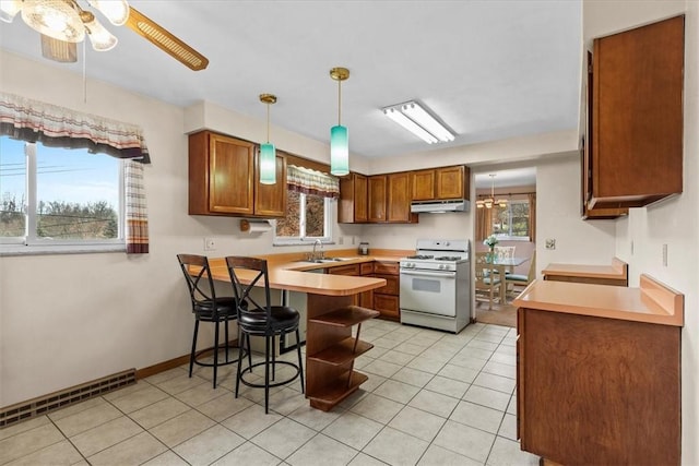 kitchen with sink, kitchen peninsula, pendant lighting, a breakfast bar area, and white gas range oven