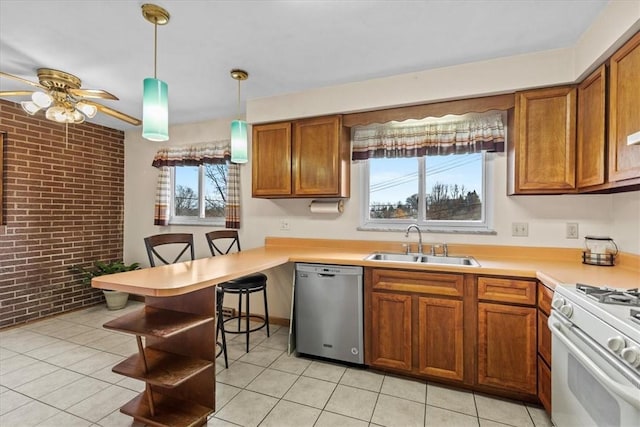 kitchen with dishwasher, hanging light fixtures, sink, white gas stove, and brick wall