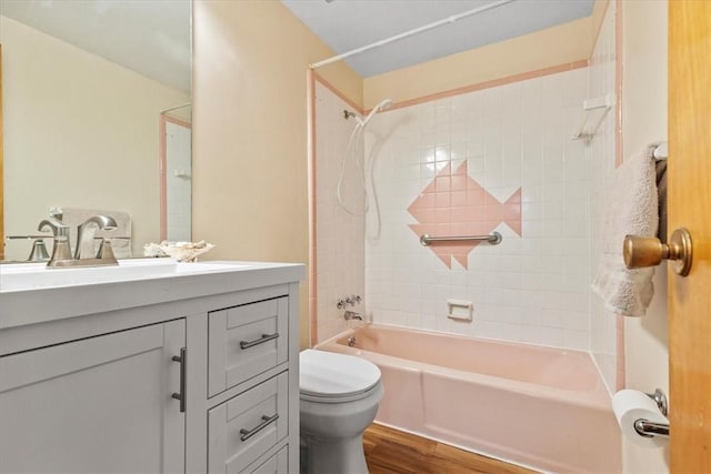 full bathroom featuring hardwood / wood-style flooring, tiled shower / bath combo, toilet, and vanity