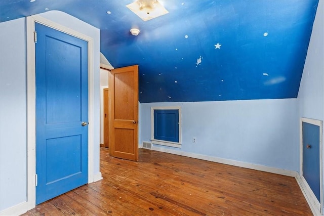 additional living space with hardwood / wood-style floors and lofted ceiling