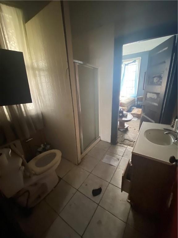 bathroom with toilet, vanity, tile patterned floors, and a shower with door