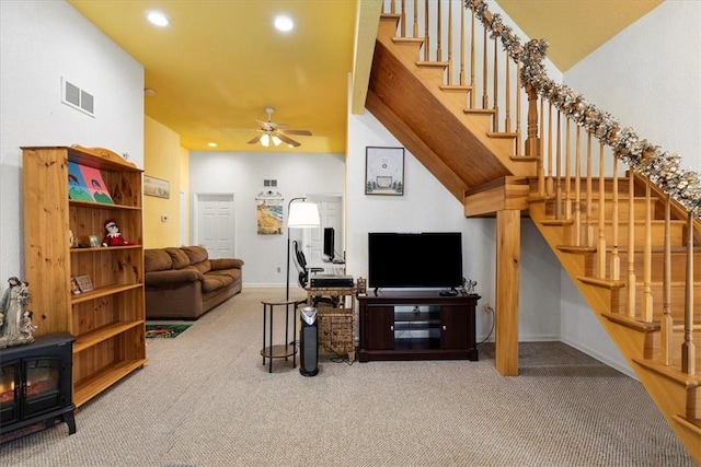 living room featuring ceiling fan, a wood stove, and carpet flooring