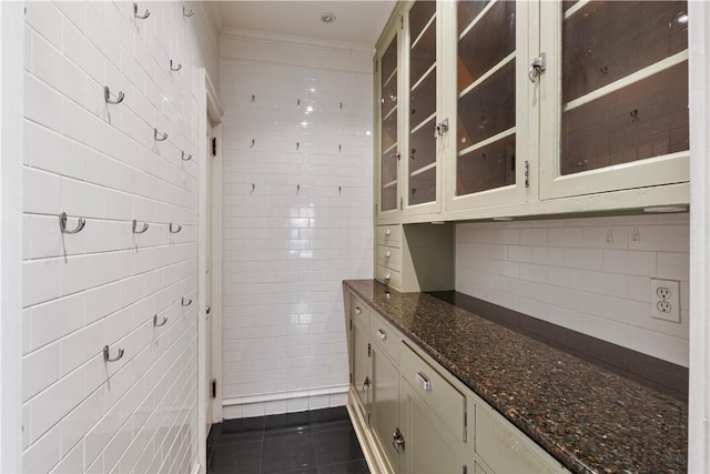 interior space featuring dark stone countertops, dark tile patterned floors, tile walls, tasteful backsplash, and cream cabinetry