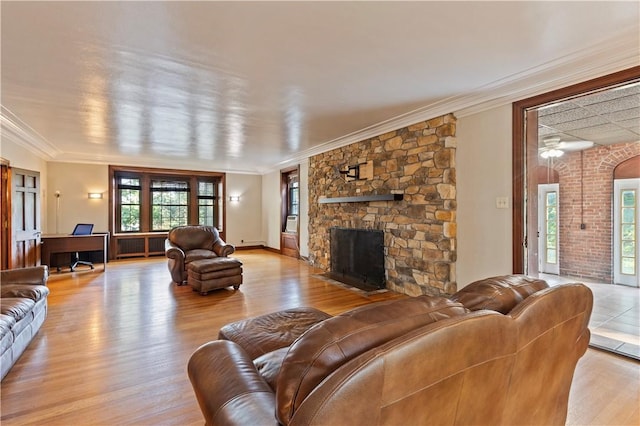 living room with a fireplace, crown molding, light hardwood / wood-style flooring, and ceiling fan