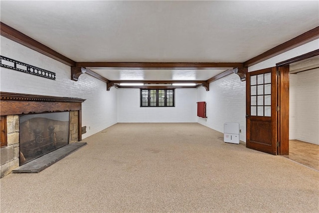 unfurnished living room featuring beam ceiling, light colored carpet, and a stone fireplace