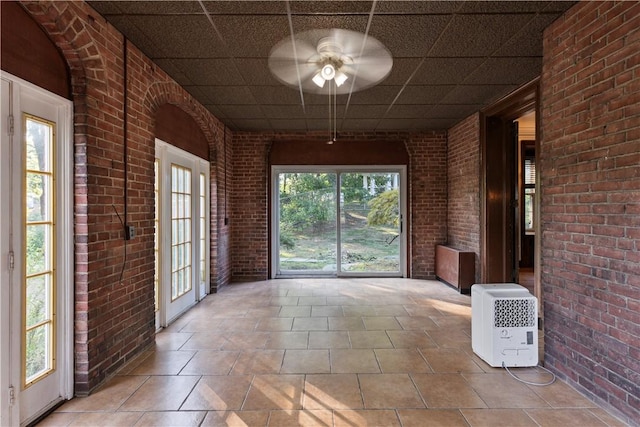 unfurnished sunroom with ceiling fan and a drop ceiling