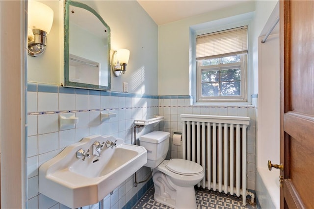 bathroom featuring tile patterned floors, sink, toilet, tile walls, and radiator heating unit