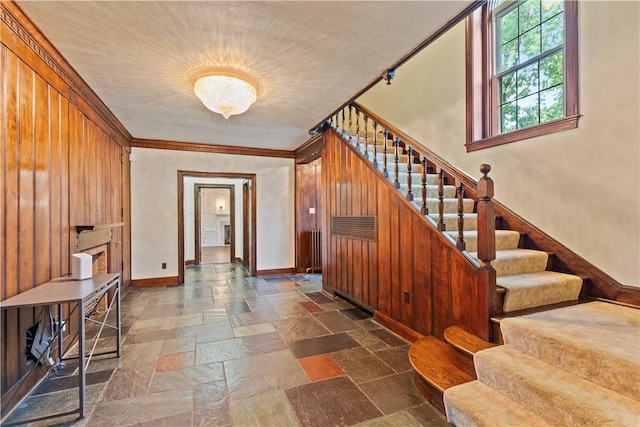 entrance foyer with crown molding and wood walls