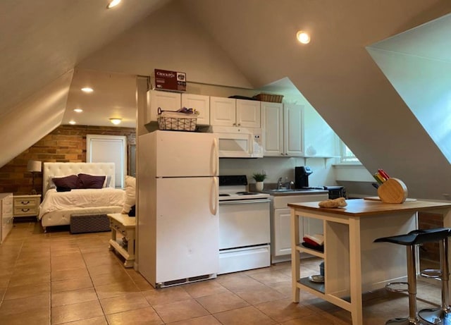 kitchen with white appliances, sink, white cabinetry, lofted ceiling, and light tile patterned flooring