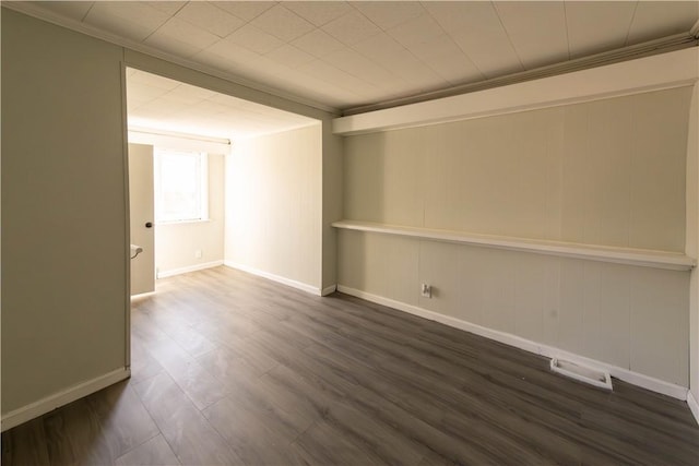 spare room with dark hardwood / wood-style flooring, ornamental molding, and wooden walls