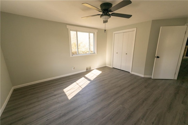 unfurnished bedroom with ceiling fan, dark hardwood / wood-style floors, and a closet