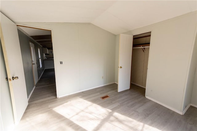 unfurnished bedroom featuring lofted ceiling, wood-type flooring, and a closet