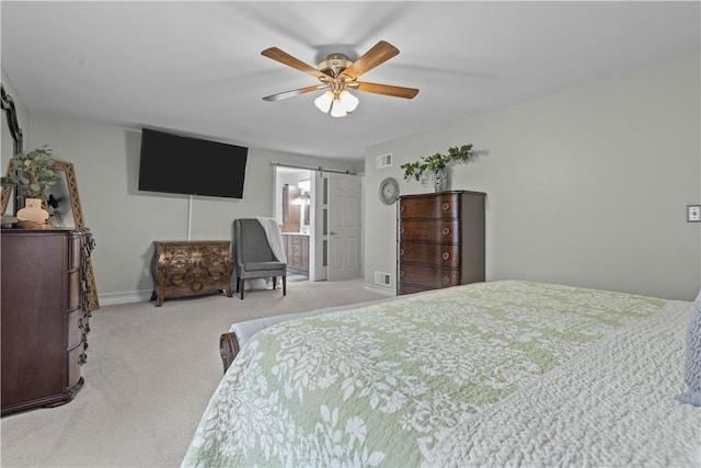 carpeted bedroom featuring a barn door, ensuite bath, and ceiling fan