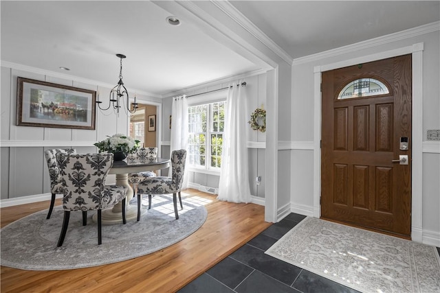 foyer with dark wood-type flooring, a notable chandelier, and ornamental molding