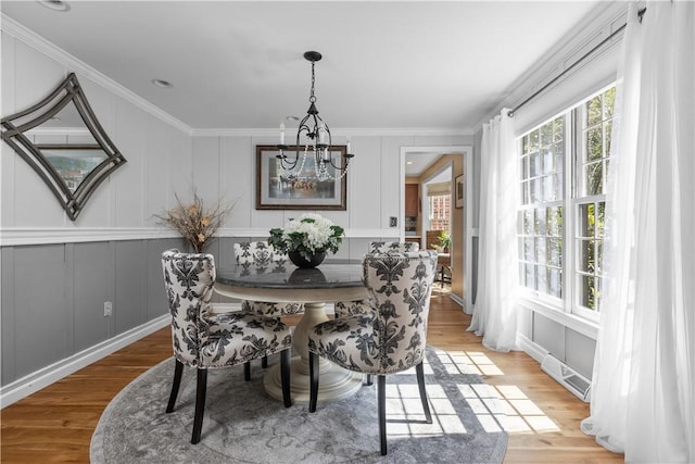 dining area featuring a notable chandelier, wood-type flooring, and crown molding