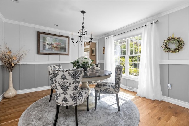 dining area with a chandelier, hardwood / wood-style floors, and crown molding