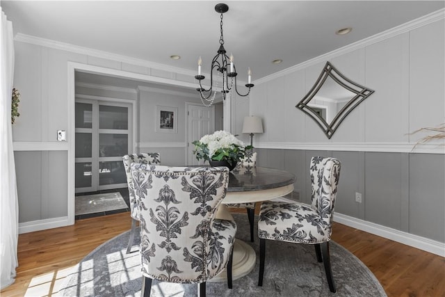 dining space with a chandelier, light wood-type flooring, and crown molding