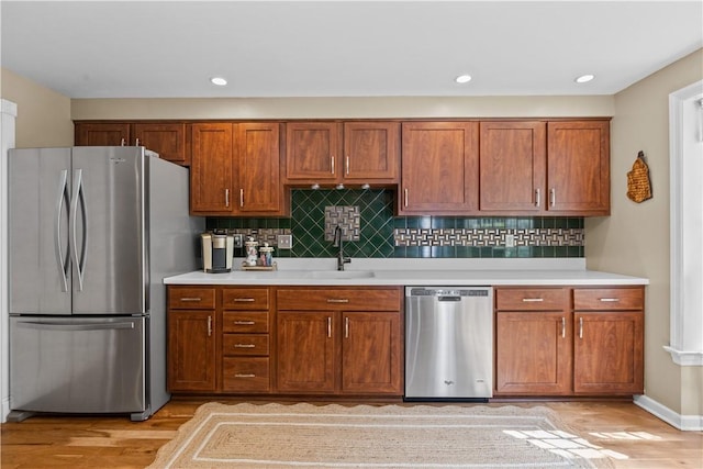 kitchen featuring tasteful backsplash, sink, appliances with stainless steel finishes, and light hardwood / wood-style flooring