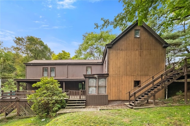 back of house featuring a sunroom, a deck, and a lawn