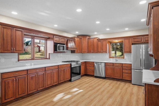 kitchen with sink, stainless steel appliances, tasteful backsplash, and light hardwood / wood-style flooring