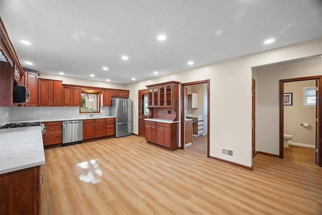 kitchen featuring light wood-type flooring, stainless steel appliances, and tasteful backsplash