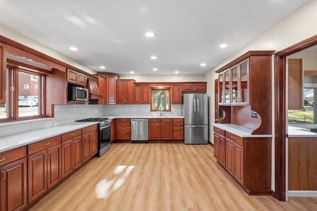 kitchen with backsplash, sink, stainless steel appliances, and light hardwood / wood-style flooring