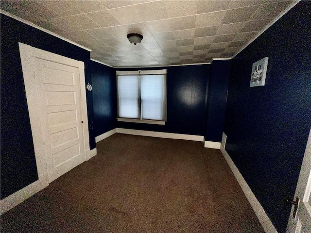 empty room featuring dark carpet and ornamental molding