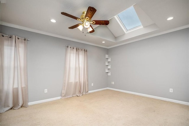 carpeted spare room featuring ceiling fan, crown molding, and vaulted ceiling with skylight