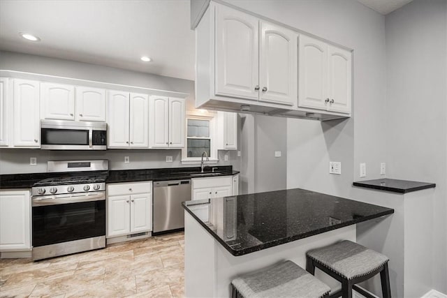 kitchen featuring a breakfast bar, white cabinets, sink, kitchen peninsula, and stainless steel appliances