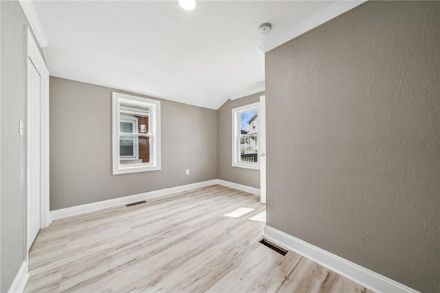 spare room with light hardwood / wood-style flooring and lofted ceiling