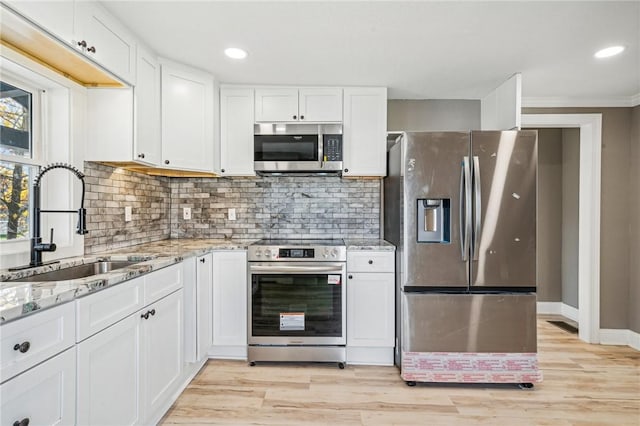 kitchen with sink, light hardwood / wood-style flooring, light stone counters, white cabinetry, and stainless steel appliances