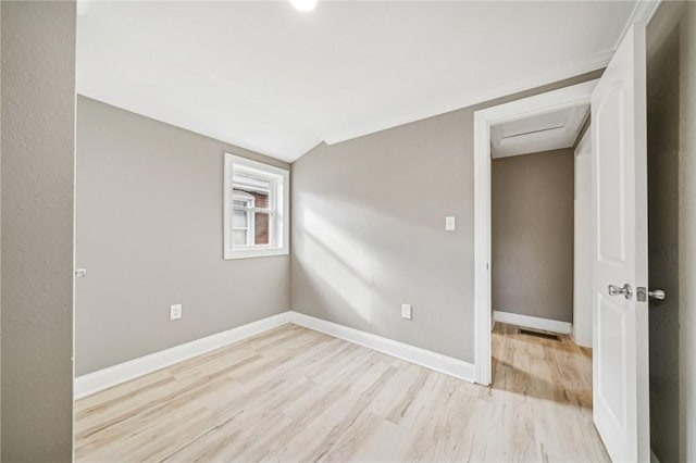 empty room featuring light wood-type flooring and crown molding