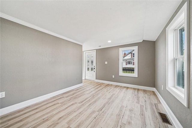 spare room featuring plenty of natural light, light hardwood / wood-style floors, lofted ceiling, and ornamental molding