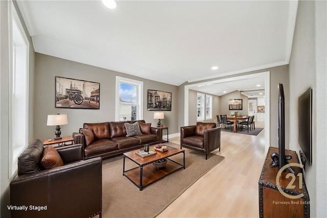 living room featuring hardwood / wood-style flooring, a healthy amount of sunlight, lofted ceiling, and crown molding