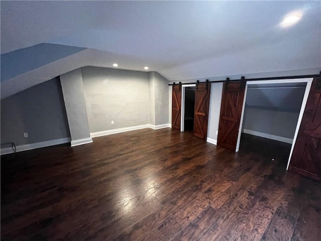 bonus room with dark hardwood / wood-style flooring, a barn door, and lofted ceiling