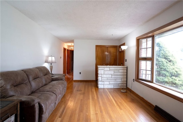 living room featuring a fireplace, a textured ceiling, and light hardwood / wood-style flooring