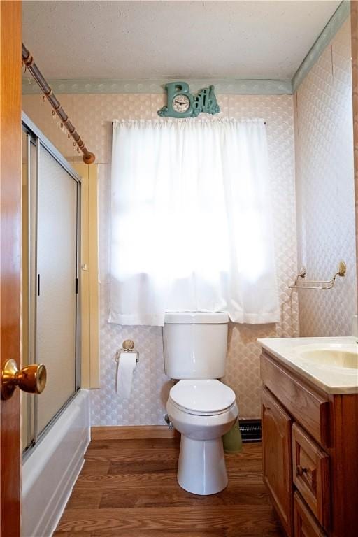 full bathroom with wood-type flooring, vanity, toilet, and enclosed tub / shower combo