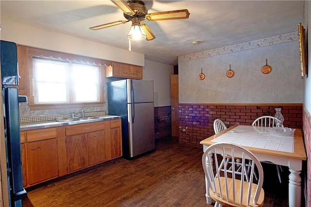 kitchen featuring ceiling fan, sink, dark hardwood / wood-style flooring, tile countertops, and stainless steel fridge