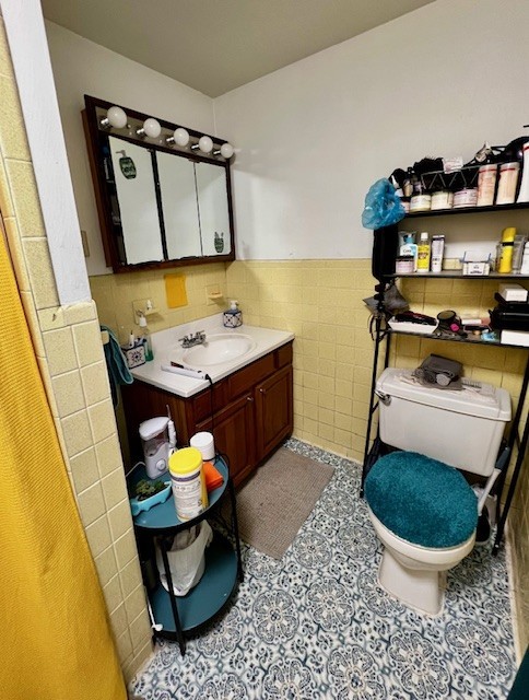 bathroom with tile patterned flooring, vanity, tile walls, and toilet