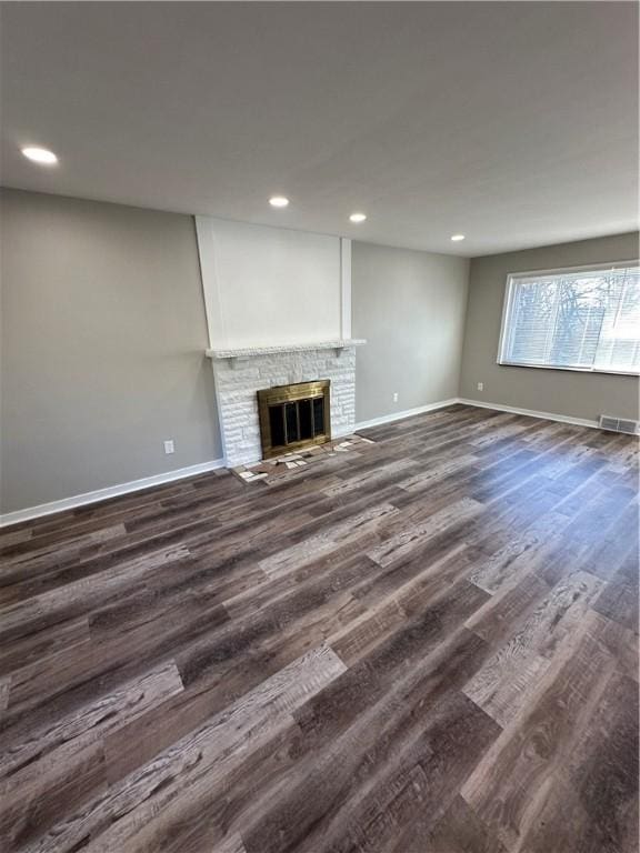 unfurnished living room with a brick fireplace and dark hardwood / wood-style flooring