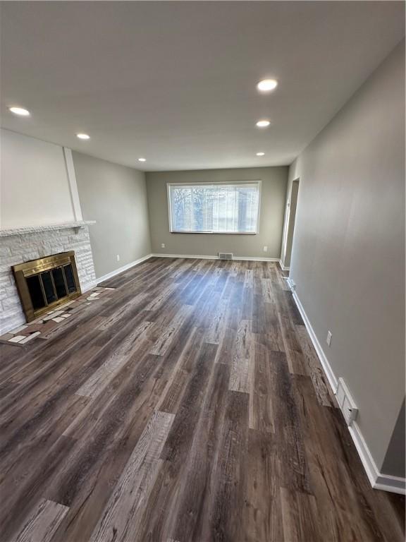 unfurnished living room featuring dark wood-type flooring and a fireplace