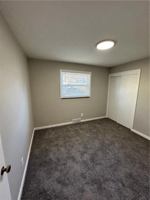 unfurnished bedroom with a closet and dark carpet