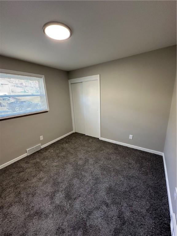 unfurnished bedroom featuring dark colored carpet and a closet