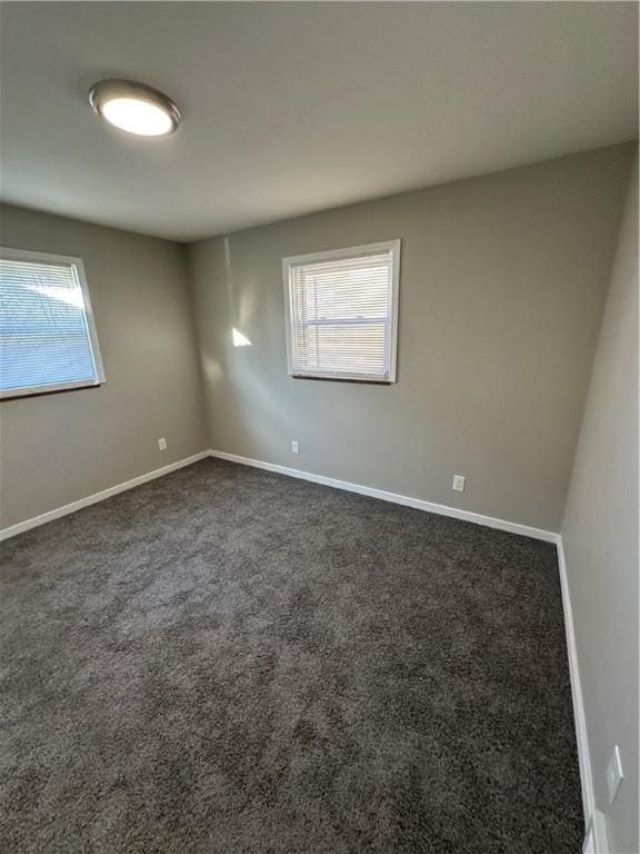 unfurnished room with a healthy amount of sunlight and dark colored carpet