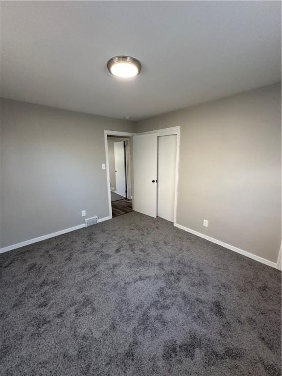 spare room featuring dark colored carpet